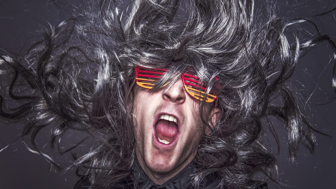 Mann mit Partybrille und wilder Perücke jubelt ausgelassen