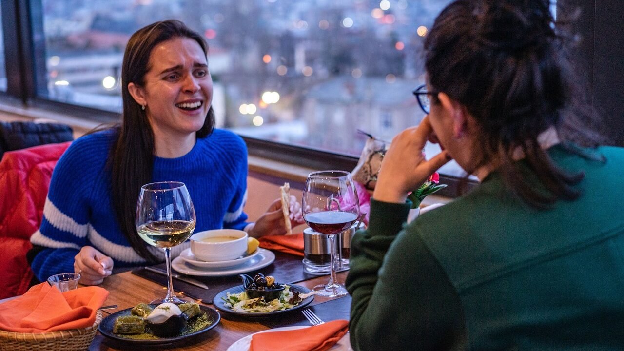 Zwei Freundinnen lachen herzlich zusammen am Tisch