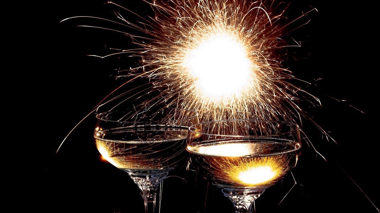 Zwei Sektgläser vor einer funkelnden Wunderkerze in der Silvesternacht